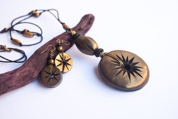 Fototapeta premium Black gold shiny boho necklace and earrings in macro. Fashion jewelry background. Handmade polymer clay jewelry.