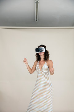 Woman wearing summer dress, dancing with VR goggles on