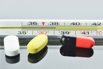 Thermometer and different pills and capsule.