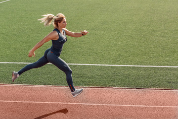 Fototapeta premium Sporty Lifestyle. Young woman on stadium running determined side view