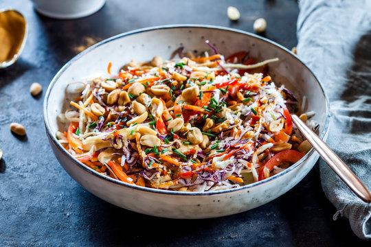 Warm rice salad with grated vegetables, peanut sauce and peanuts