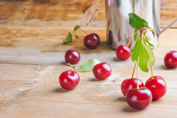 Fresh ripe sweet cherry in the steel mug on the wooden table.