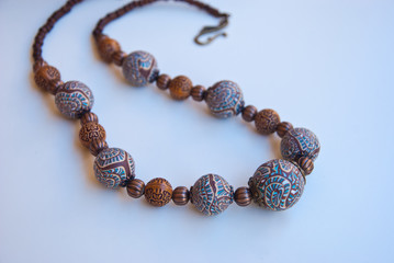 Handmade jewelry of polymer clay. Indian beaded necklace near bronze bowl. Luxury bohemian jewelry.