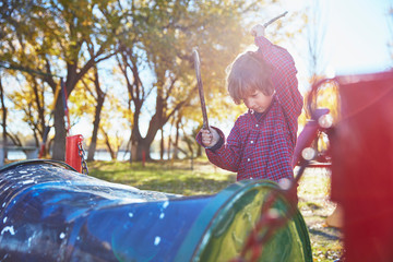 Boy drumming on cask on playground