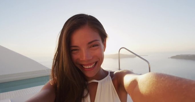 Portrait of beautiful woman taking selfie video at sunset with sunlight and flare. Selfie video POV of cute adorable multiracial asian caucasian lady at beautiful location. SLOW MOTION.