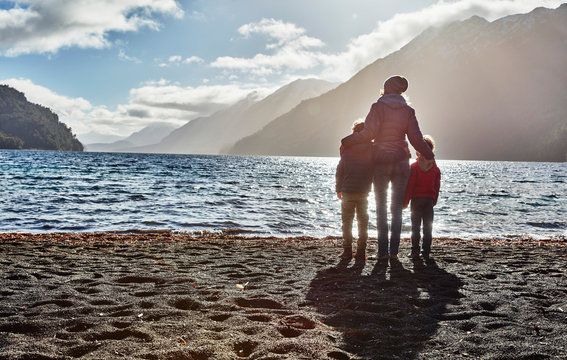 Argentina, Patagonia, Lago Nahuel Huapi, woman with two sons standing at the shore overlooking the lake