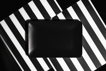 Black dish on black and white striped background