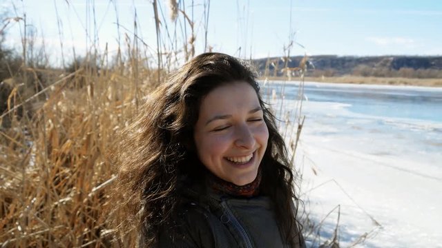 portrait of a beautiful girl on the bank of a frozen river enjoying nature, laughing and playing with yellow cane