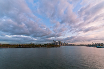 Fototapeta premium View of dramatic clouds over New York city skyline and upper Hudson River in morning from Brooklyn Cruise Terminal 