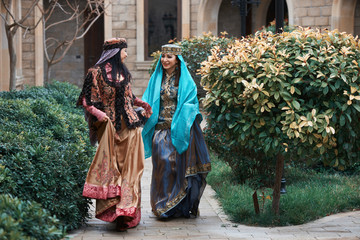 Beautiful azeri women in traditional Azerbaijani dress running by the wooden door