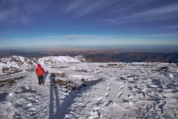 Woman backpacker girl descending from the snow covered top of Jebel Toubkal in Atlas mountains...
