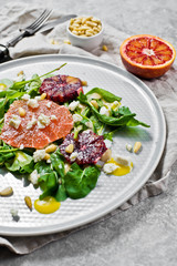 Vegetarian salad with arugula, grapefruit, red oranges, nuts and tofu cheese. Gray background, side view, close-up