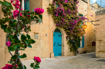 Fototapeta na wymiar Mdina, Malta: traditional Maltese limestone house with bright purple flowers