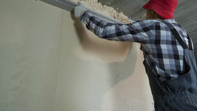 builder leveling plaster on aerated concrete block wall with construction ruler