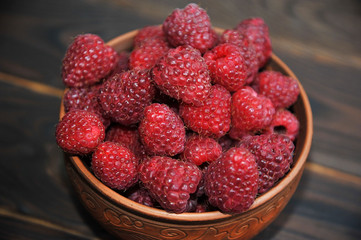 beautiful clay dish with raspberries on a napkin, on a wooden table. View from above.