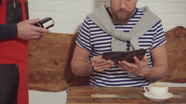 Waiter is waiting a payment by card of male customer in cafe