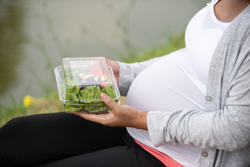 pregnancy, take away food healthy concept - close up of happy pregnant woman eating vegetable salad for breakfast