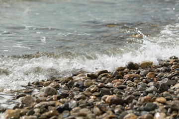 Fototapeta na wymiar Close to a pebble beach against the backdrop of sea waves