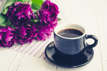 Cup of coffee with bouquet of ultraviolet tulips