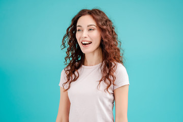 Fototapeta premium Attractive brunette girl with curly hair isolated over blue turquoise background smiling and laughing