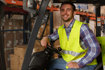 Forklift operator sitting in vehicle, posing and smiling. Handsome man wearing reflective coat...