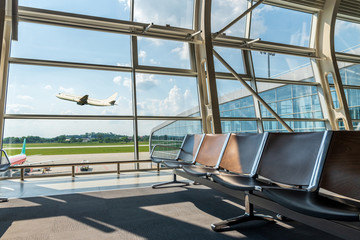 Lounge in airport terminal and passenger plane flying over sky. Summer vacation and travel concept