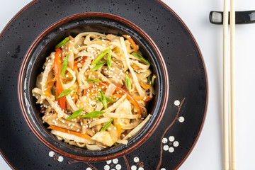 Japanese ramen soup with chicken, egg, chives and sprout on dark wooden background.