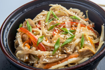 Japanese ramen soup with chicken, egg, chives and sprout on dark wooden background.