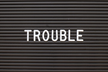 Black color felt letter board with white alphabet in word trouble background