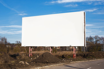Empty copy space blank white billboard with blue cloudy sky in the background.