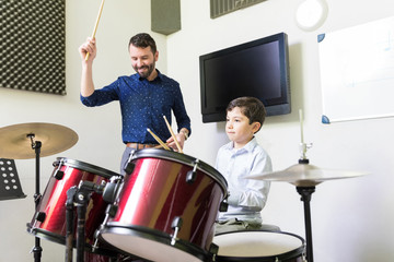 Music Teacher Giving Drum Lessons To Little Boy