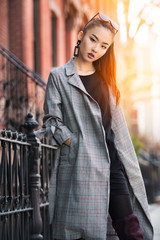 Beautiful young Asian fashion model woman walking on city street wearing jacket and sunglasses
