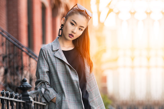 Beautiful young Asian fashion model woman walking out from home in big city at sunny day