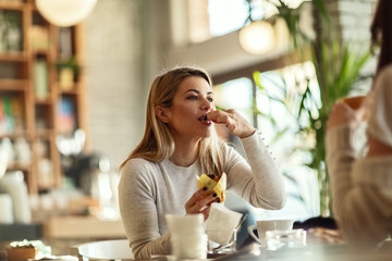 Young beautiful woman eating muffin in a cafe.