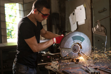 Man cutting metal frame with compound mitre saw with sharp circular blade.
