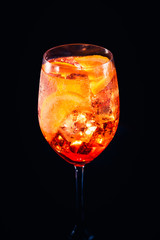 Stylish alcoholic aperol spritz cocktail with orange slice on black background.