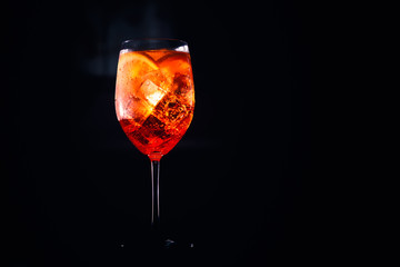 Tasty alcoholic aperol spritz cocktail with orange slice on black background.