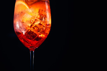 Tasty alcoholic aperol spritz cocktail with orange slice on black background.