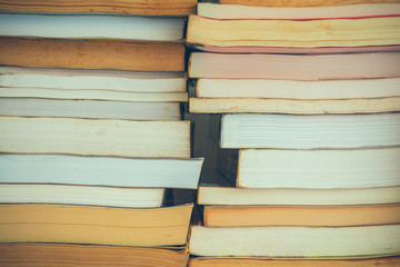 Stack of many old books background on shelf in book store or library room, vintage tone. Knowledge learning, education, bachelor degree in university or back to school concept.