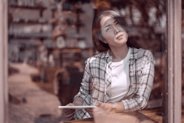 woman using digital tablet and thinking in cafe