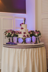 White three tier wedding cake with purple flowers decor