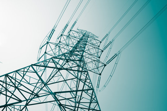 Abstract pattern from bottom view of high voltage pole power transmission tower with clear sky sunny day background in monochrome tone. Green energy, environmental conservation concept.