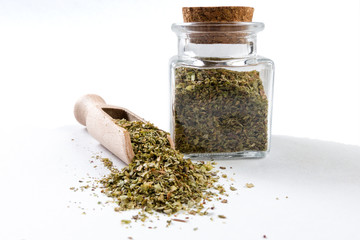 marjoram in wooden scoop and jar on isolated on white background