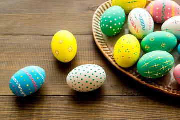 Easter traditions. Colorful Easter eggs in basket on dark wooden background top view copy space