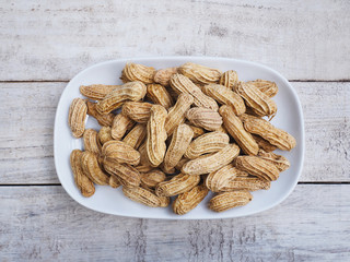 boiled peanuts on plate over  wooden table.