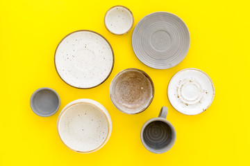 Kitchen concept. Crockery kit. Empty ceramic plates and mugs on yellow background top view