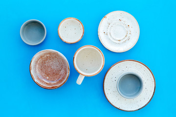 Kitchen concept. Crockery kit. Empty ceramic plates and mugs on blue background top view