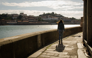 young woman seen from behind walking on a riverside boardwalk