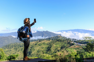 Fototapeta na wymiar young asian women backpack tourists checking signal 4g gps and map on smartphone on the mountain and mountain fog clear sky background