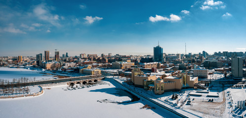 Fototapeta premium Aerial drone panorama; beautiful view Chelyabinsk city with white snowy streets and bridges; sunny winter day in South Ural capital; industrial and pollution problem; undeveloped urban environment